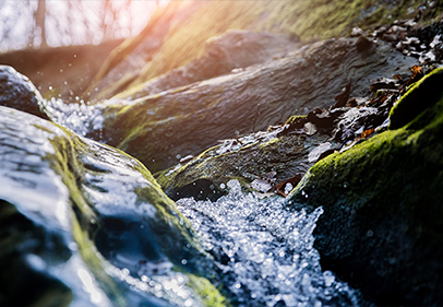 Close up image of water flowing through a creek symbolizing sustainability and nature.
